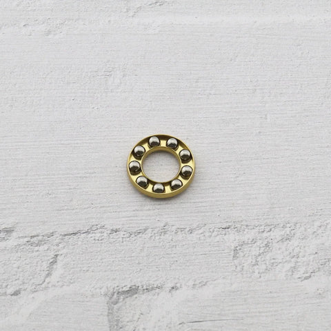 Thrust ball bearing with a gold-colored outer race and eight chrome balls around the inner bore; miniature size.