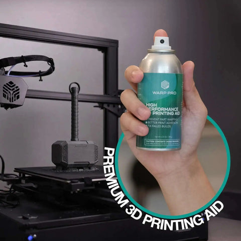 Hand holding a spray can labeled "High Performance Printing Aid" near a 3D printer, showing Pro Grade 3D Printer Bed Adhesive Spray For Warp Free Prints Easy Spray On Build Plate Solution That Is Water Washable No More Glue Sticks Works With All Filaments And Build Surfaces.
