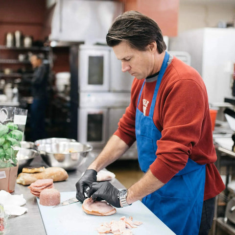 Chef using Black Nitrile Disposable Gloves 3 Mil Powder Free Food Safe X Large Box Of 100 while slicing ham in kitchen