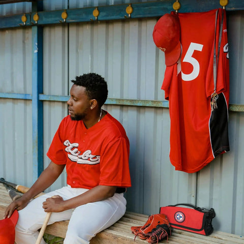 Baseball player sitting with Ready To Go 73 Piece Coaches And Team Sports First Aid Kit In Roll Up Bag on bench