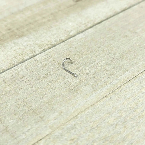 20 Gauge Nose Stud In Stainless Steel 316L With Clear Accent Micro Screw Head, 6mm Length on wooden surface