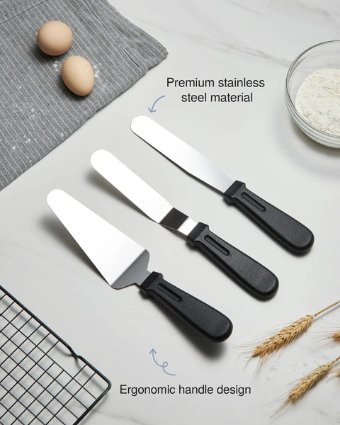 Three stainless steel icing spatulas with ergonomic handles on a kitchen counter