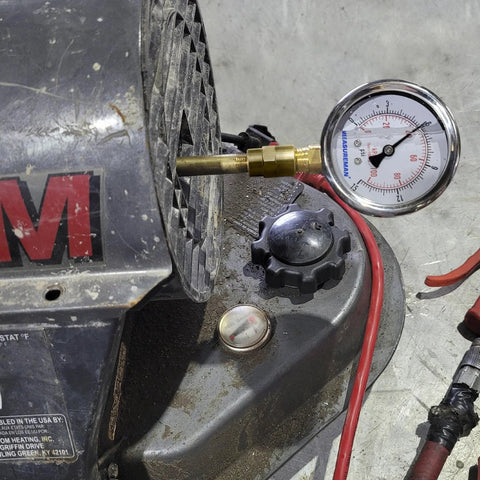 MeasureMan air gauge kit with brass adapter and red hose attached to a portable oil-fired heater.