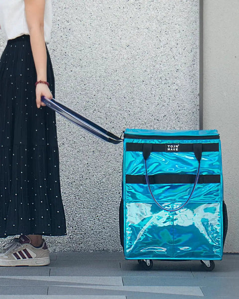 Person pulling Glitter Blue Rolling Grocery Tote With Wheels And Zipper Covered 8 Pocket Organizer on sidewalk