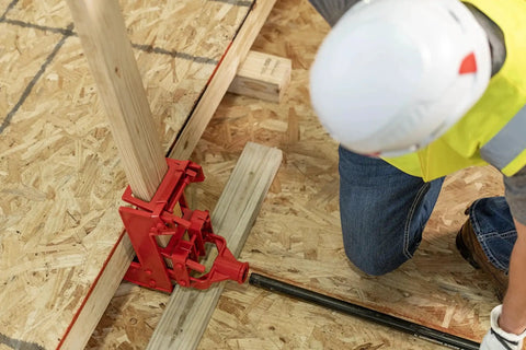 Portable Wall Jack 1000 Lb Capacity For Raising Walls And Beams installed on plywood with worker adjusting lever