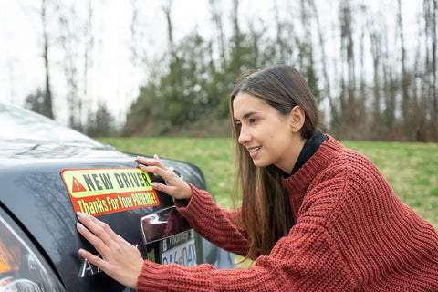 Person installing Extra Large Driver Sign For Car 3 Pack Magnetic Bumper Stickers Yellow Reflective Road Safety Sign For Learners And Beginner Drivers Fits Most Vehicles on a vehicle.