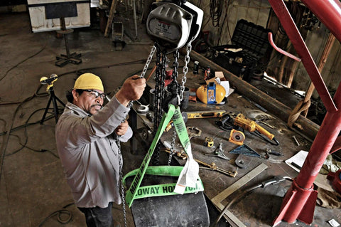 Worker using 3 Ton Hand Chain Hoist With 15 Ft Lift, Industrial Grade Wire Rope Hoist, Model S90-300-15 in a workshop setting.