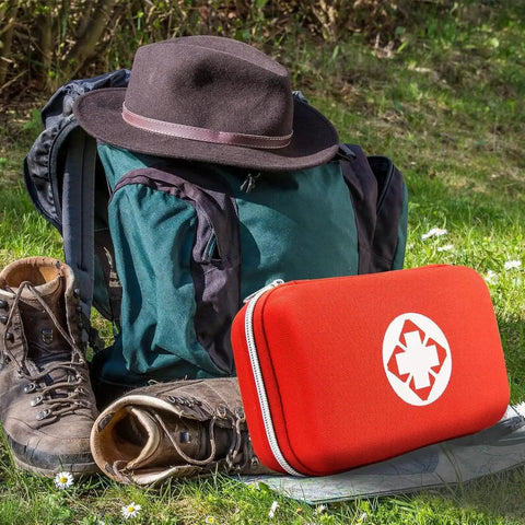 Car First Aid Kit 275 Piece Grab And Go Survival Gear in red EVA case with hiking gear on grass