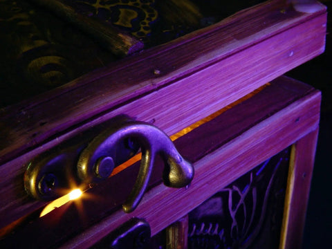 Close-up of wooden chest with decorative handle and intricate design, partially opened with light shining through.