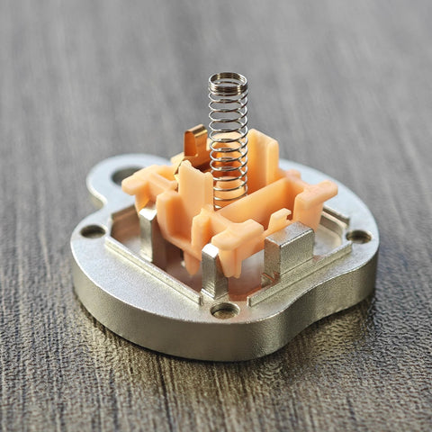 Cherry MX switch core with peach plastic housing and vertical stainless steel spring.