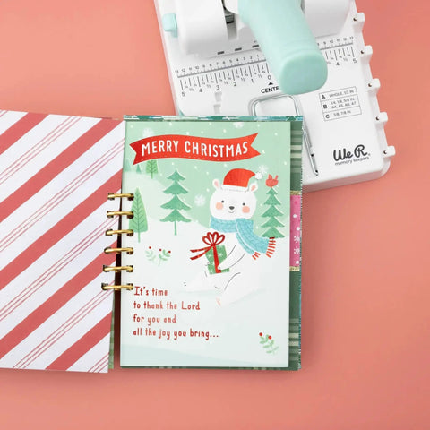 Mini Cinch Binding Tool For DIY Books And Notebooks With Wire Or Spiral Coils Pro Grade Mini Binding Machine next to a Christmas-themed notebook