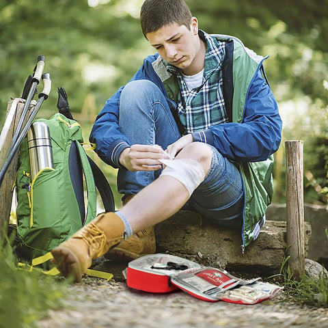 Man using 2 In 1 First Aid Kit Set With 215 Hospital Grade Items Plus 43 Piece Mini Kit for travel, in outdoor setting.