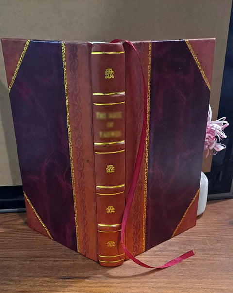 Front view of burgundy leather-bound book with gold tooling, in a maroon case with purple side panels and red ribbon