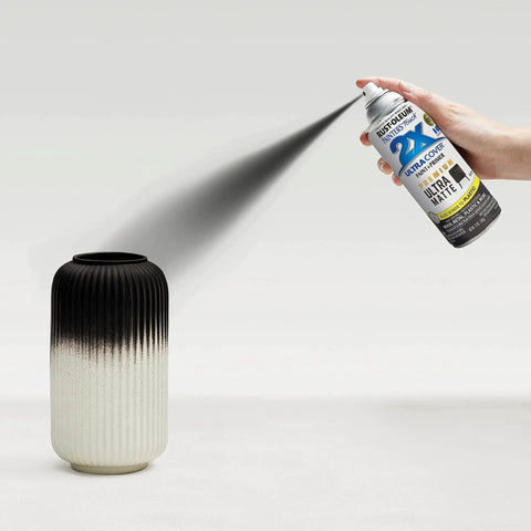 Hand using Oil Based Spray Paint For Interior And Exterior Matte Black 12 Oz 2X Ultra Cover on a ceramic vase