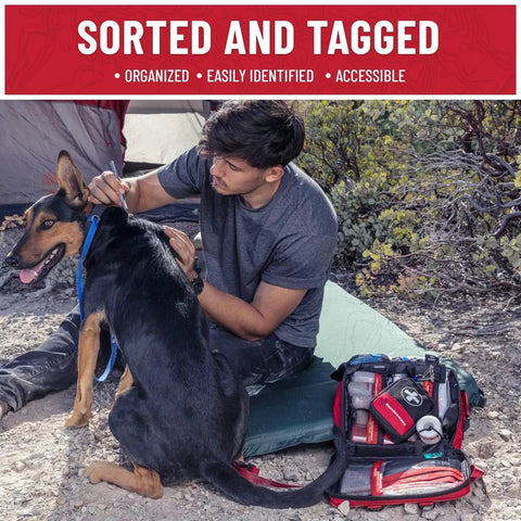 Man using Comprehensive 238 Piece Survival First Aid Kit For Travel Camping And Home Use with labeled compartments outdoors with dog