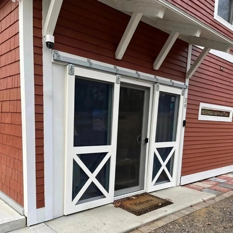 Exterior doors on a red barn with Beefy Heavy Duty Box Rail Hanger Bracket For Barn Doors, Rugged Rail Mount Bracket For Exterior Doors, Silver Finish, Easy Install, Compatible With Standard Barn Door Rail Systems, 8 Pack installed.