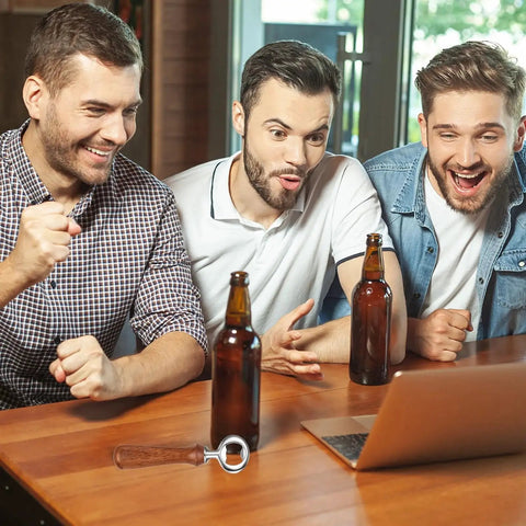 Three men enjoying drinks with a laptop and a Bulk 15 Piece Metal Bottle Opener Kit With Zinc Alloy Inserts on a wooden table.