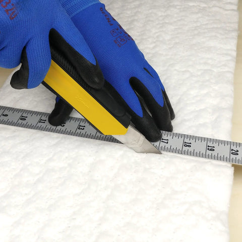 White ceramic fiber insulation blanket, 1/4 in thick, 16 x 240 in, being cut with a utility knife.