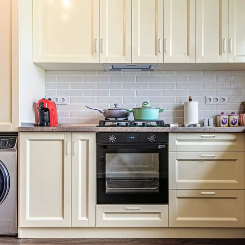 White kitchen with cream cabinets, modern appliances, granite countertop, and backsplash
