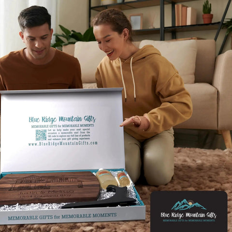 Couple opening Personalized New Homeowners Cutting Board With Custom Home Image Laser Engraved Wooden Chopping Board In Cherry Maple Or Walnut For The Housewarming Gift And Realtor Closing Gift That Rocks From Blue Ridge Mountain Gifts box on the floor.