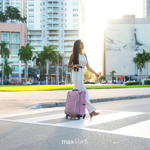 Woman crossing street with Ultra Lightweight 21 Inch Carry On Luggage With 4 Spinner Wheels Expandable Softside Suitcase for Travel
