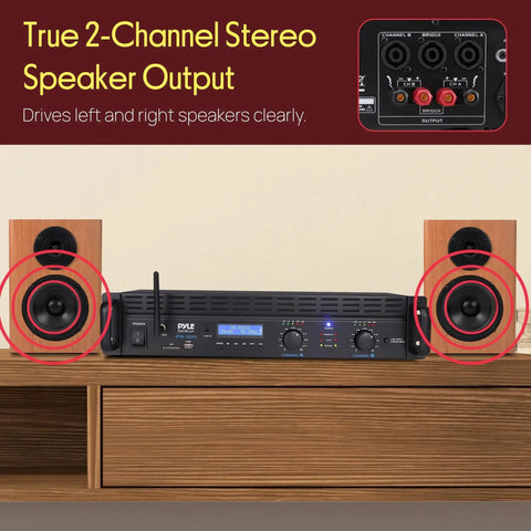 2 Channel Rack Mount Power Amplifier With Bluetooth 2000W Peak Bridgeable, front view with speakers, displayed on a wooden surface.