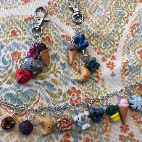 Colorful jewelry pieces with charms on a patterned fabric background showcasing uses for 300Pcs Mini Screw Eye Pins and Hooks Set 10x5mm.