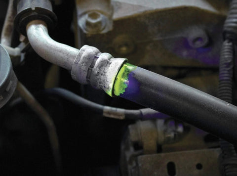 Car Leak Detection Kit For AC And Auto Fluids With Oil Based Dye, UV Light highlighting leak on metal pipe in engine bay