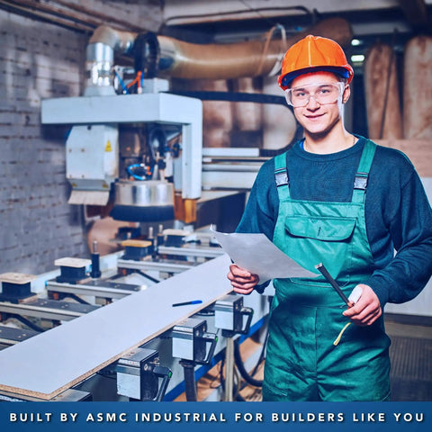 Worker in protective gear holding documents and tools in an industrial workshop setting with machinery.
