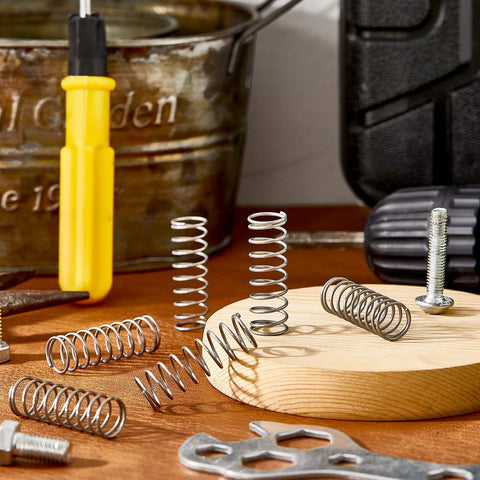 6-piece SP 9706 stainless steel extension springs, 1/2 in x 1-1/2 in, on a wooden workbench with tools
