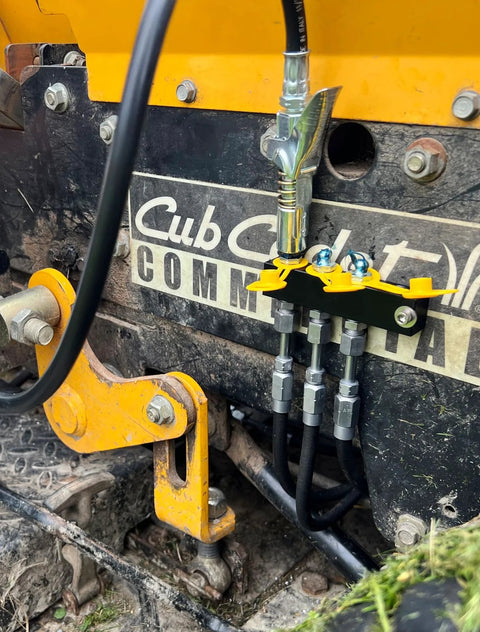 LockNLube grease fitting caps, yellow, mounted on a black bracket with metal fittings.