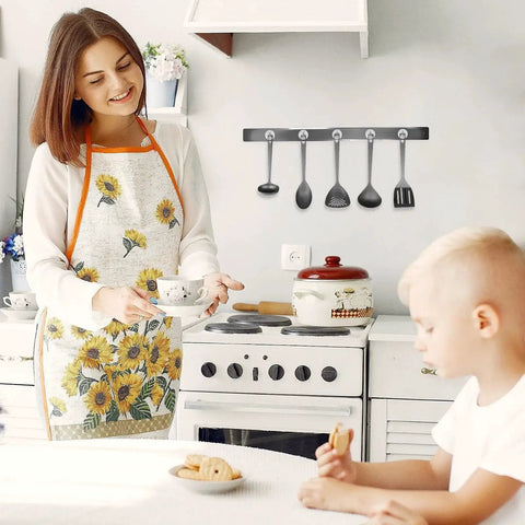 Woman in sunflower apron in kitchen near hooks holding utensils with 80lb Heavy Duty Magnetic Hooks For Cruise Cabins Refrigerator Grill And Travel