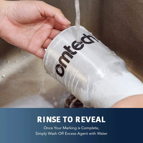 Person rinsing metal cup marked with OMTech logo after using High Contrast Metal Laser Marking Spray For CO2 And Fiber Lasers, 13oz Aerosol Black Ink For Aluminum, Stainless Steel, Brass And More, Creates Permanent Dark Marks On Bare Metal With 25W Or Higher Engravers By OMTech