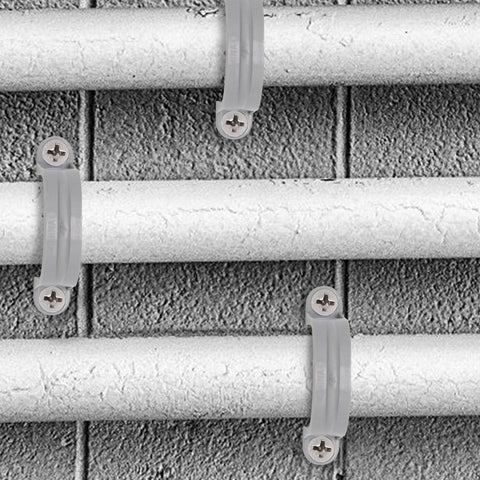 Grey 2-inch PVC pipe strap clamps, 2-hole conduit supports, 4 shown securing pipes to a brick wall.