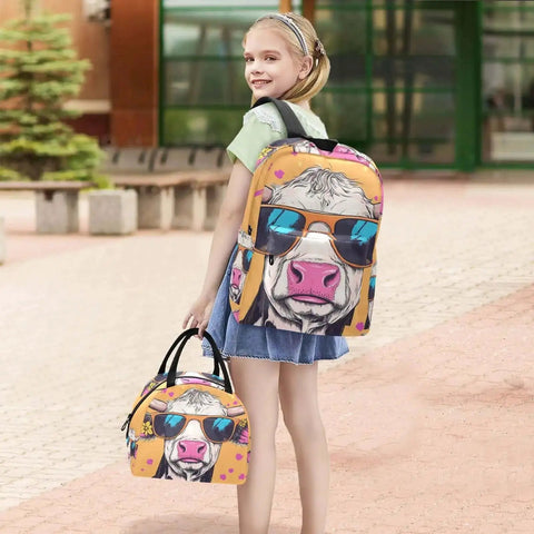 Child carrying a colorful backpack and lunch bag set with cow design, outdoors.