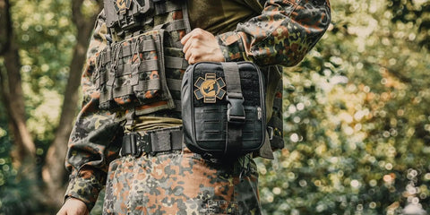 Person holding IFAK Trauma Kit with CAT Tourniquet MOLLE Pouch in black for military combat and everyday readiness in a forest setting.