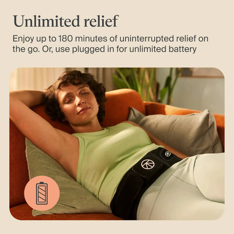 Woman relaxing on sofa wearing Four In One Back Wrap With Heat, Far Infrared, Vibration, And LED Therapy For Epic Lower Back Pain Relief At Home.