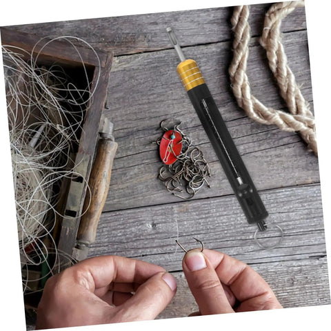 Stainless Steel Detacher Tool for Quick Release and Deep Hook Removal lying next to fishing hooks and line, shown in outdoor setting.