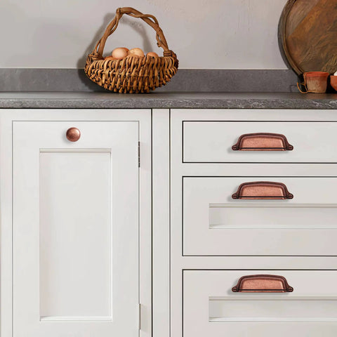 Antique Copper Cabinet Knobs 5 Pack One And A Quarter Inch Zinc Single Hole Center Pulls For Kitchen Cabinets And Drawers Vintage Retro Hardware Classic Rustic Cabinet Knobs For Home Renovation installed on white kitchen cabinets and drawers with basket and decor.