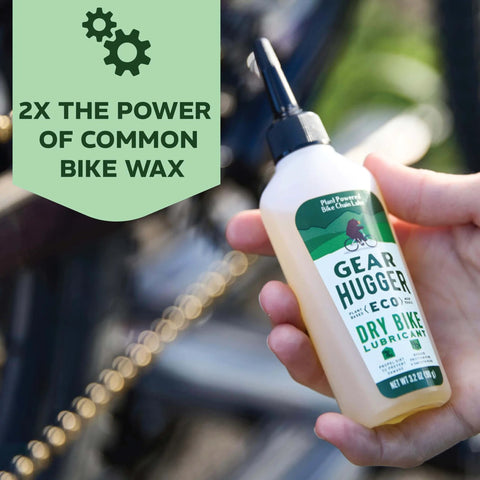 Hand holding Plant Powered Bike Chain Lubricant 3.2 Oz Pack Of 1, Eco Friendly No Teflon No Petroleum No PTFE near a bike chain
