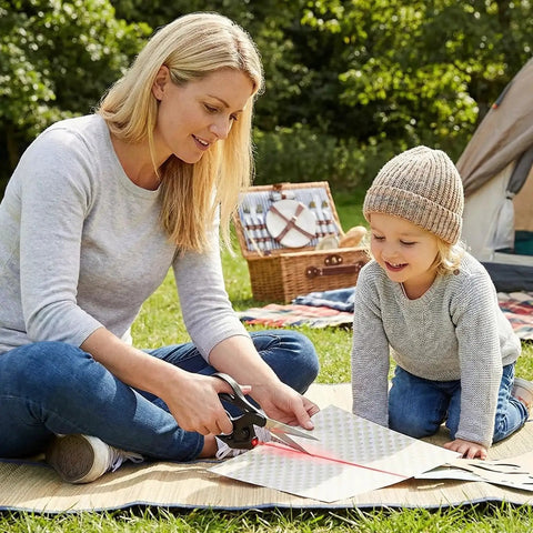 A woman using Laser Guided Scissors For Fabric Cutting And Sewing With Precision Laser Line, Quilting And Crafting outdoors.
