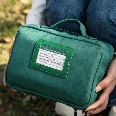 Person holding a green Pet First Aid Kit For Dogs And Cats With Thermometer And Disposable Booties by Rhino Rescue, outdoors.