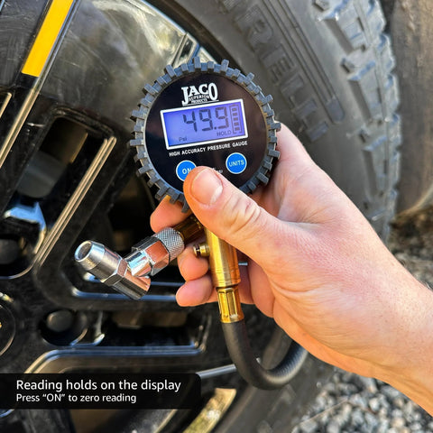 JACO ElitePro digital tire pressure gauge, black gear-edge case, display reads 49.9 psi, connected to tire inflator hose