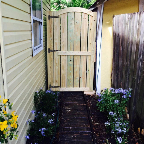 Wooden garden gate installed with 6 Pack 8 Inch T Strap Hinges Heavy Duty Shed Door Hinges Gate Strap Black Tee Hinge, surrounded by flowers.