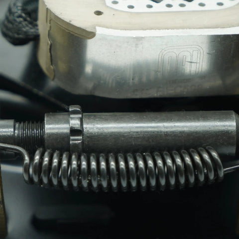 Close-up of a trailer brake magnet actuator with a coiled spring and a Dexter-branded brake rotor.