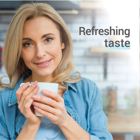 Woman with blonde hair in a denim shirt holding a white coffee cup in a kitchen; overlay text refreshing taste