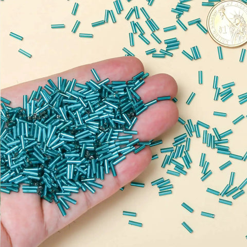 Hand holding Lake Blue Glass Bugle Beads 2x6mm Bulk 2000 Pieces Tiny Tube Beads for Jewelry Making Embroidery Sewing Crafts