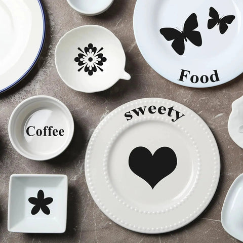 Assorted tableware with black patterns including butterflies, hearts, and text like 'Food' and 'sweety' on plates and bowls.