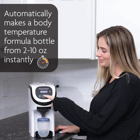 Front view of white Baby Brezza Formula Pro Mini formula mixer on kitchen counter, user pressing control panel.