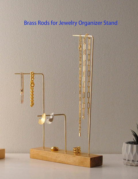 Jewelry organizer stand with brass rods displaying necklaces and earrings on a wooden base.